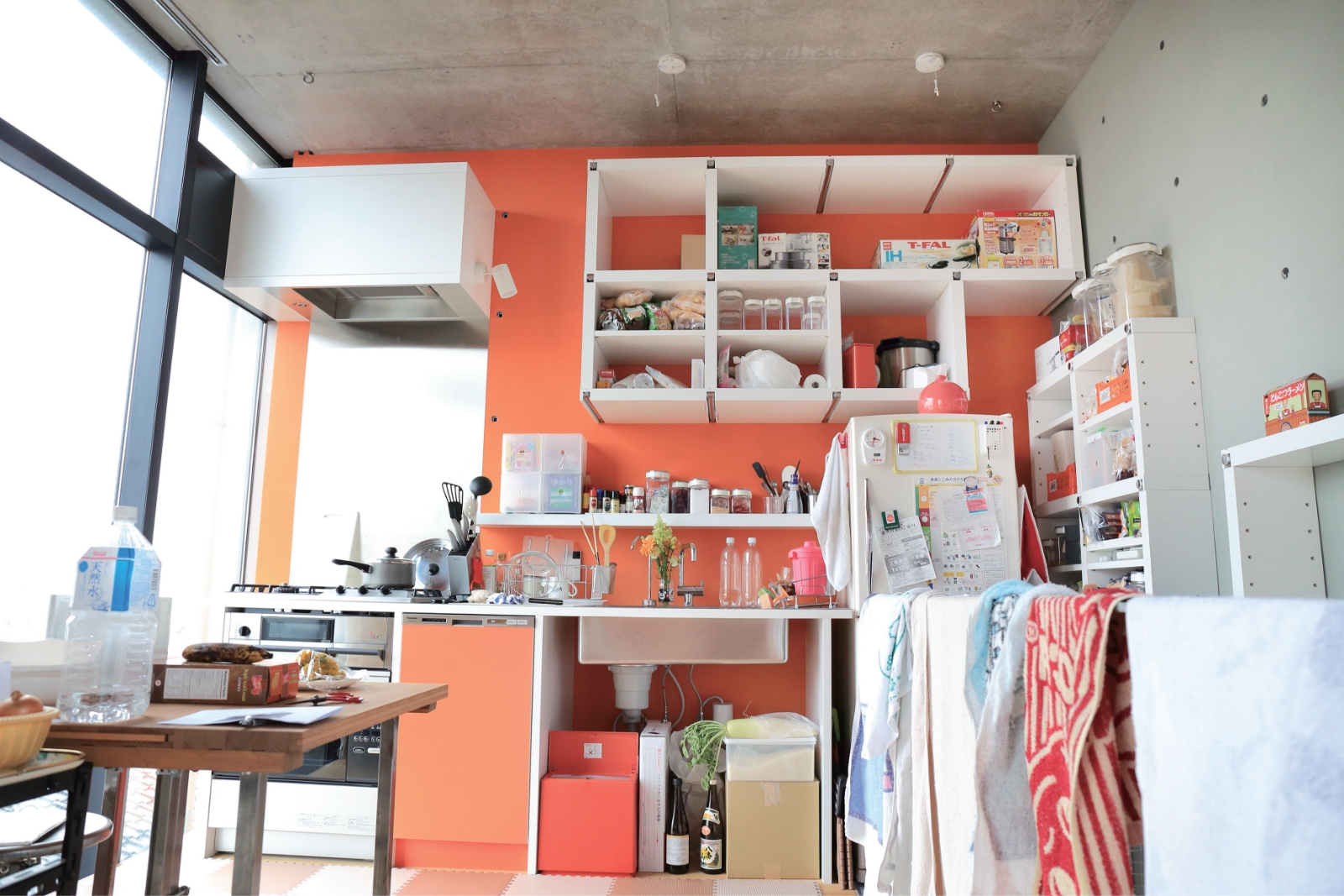 鮮やかなオレンジ色の壁のキッチン。キッチンの棚も可動式。